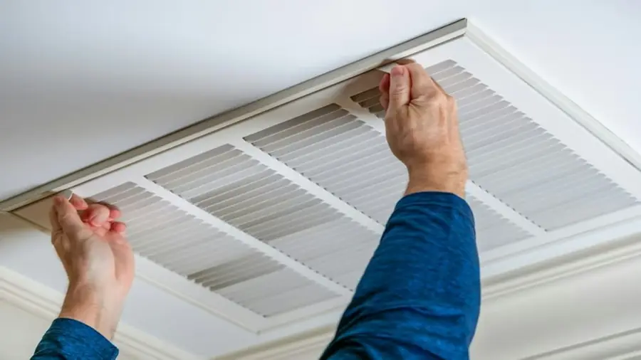 Technician fitting a ceiling return-air grille for a ducted system