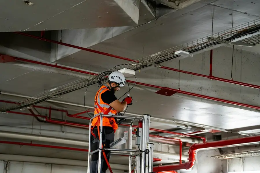 Installer on a lift working on ceiling services in a commercial building