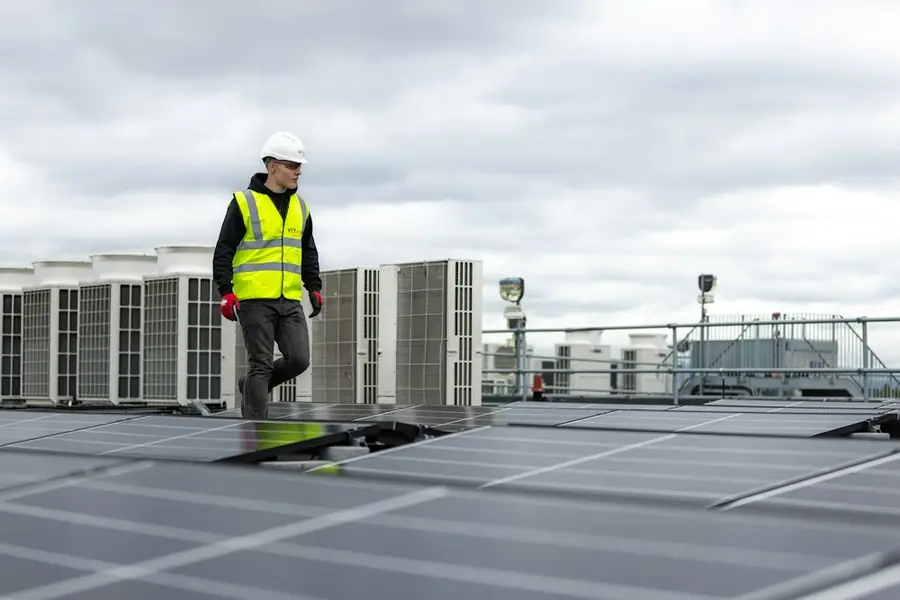 Technician walking past rooftop HVAC units during a maintenance check