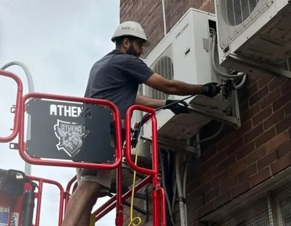 Nexus technician servicing wall-mounted outdoor units from a scissor lift